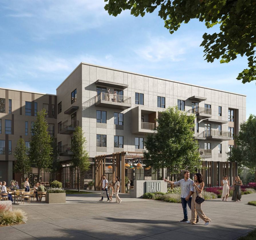 Modern apartment complex with outdoor seating, trees, and people gathered in a sunny courtyard, surrounded by multi-story buildings.