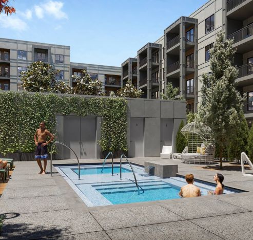 Three people enjoy a small outdoor pool and hot tub in a modern apartment complex courtyard on a sunny day.